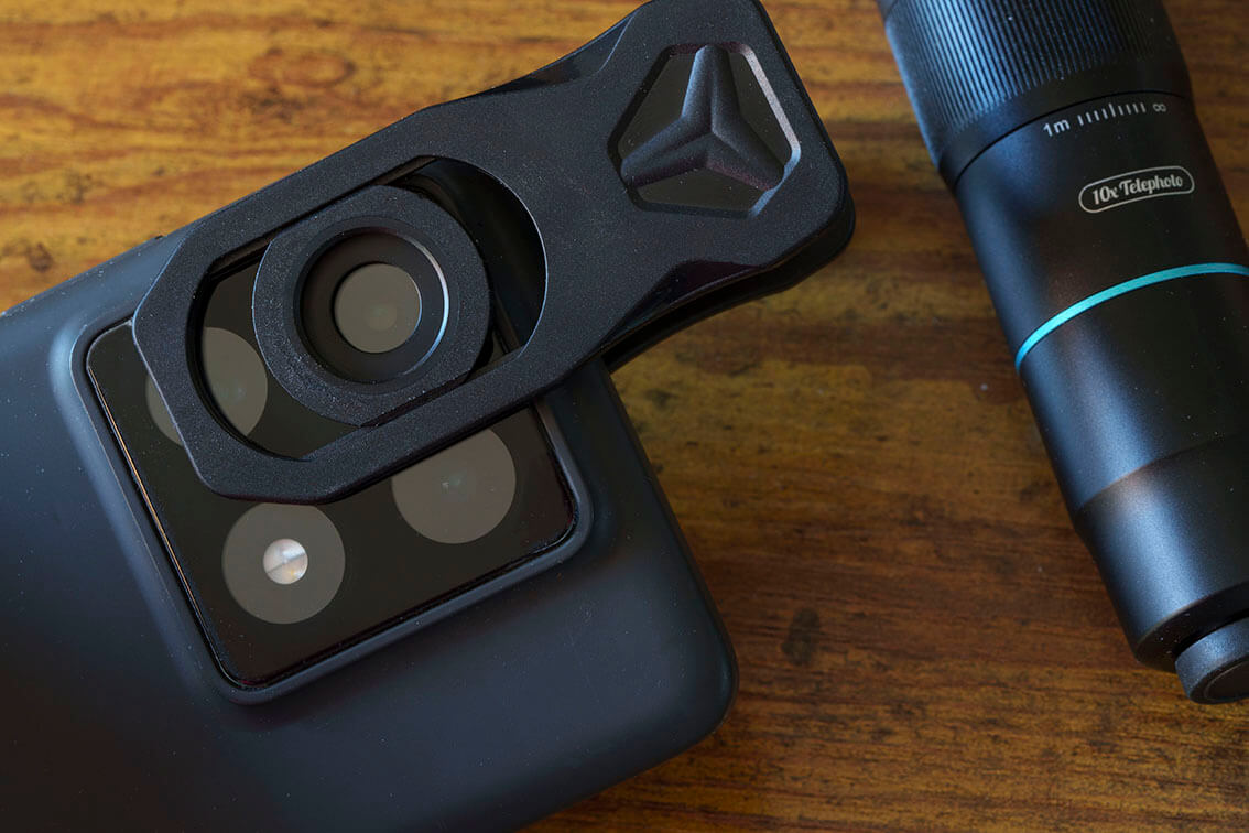 Pinza APEXEL centrada sobre la cámara de un smartphone antes de montar el objetivo