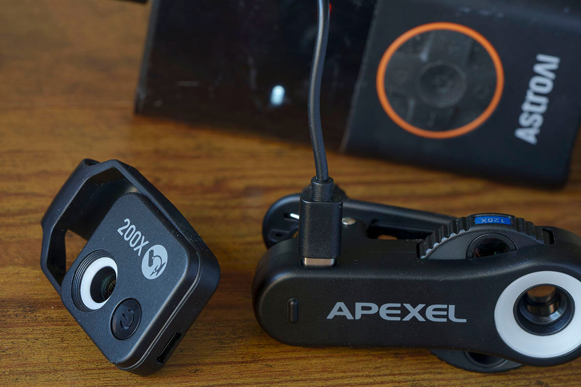 Lente APEXEL con iluminación LED y conexión USB-C recargándose desde un power bank